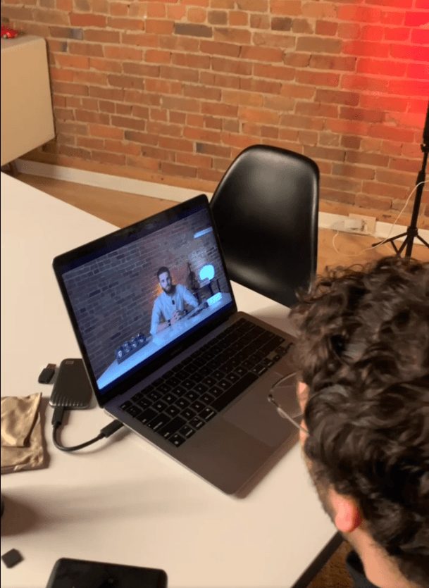Crew member viewing a recorded video on a laptop in a brick-walled room